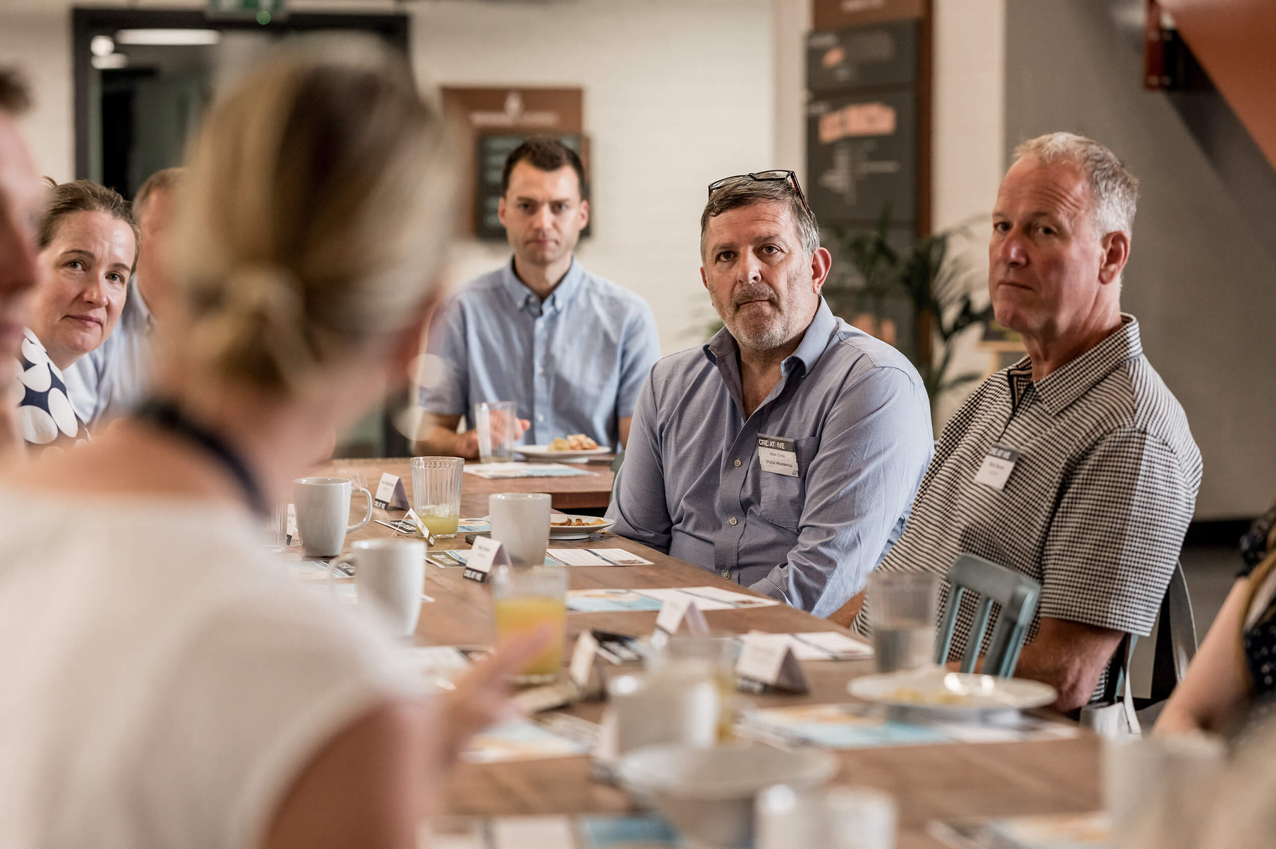 Women sat down with her back to the camera and people looking and listening