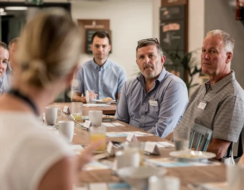 Women sat down with her back to the camera and people looking and listening Women sat down with her back to the camera and people looking and listening