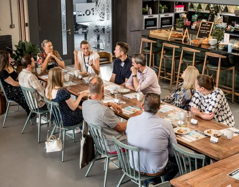 Group at the breakfast club sat around a large table talking Group at the breakfast club sat around a large table talking